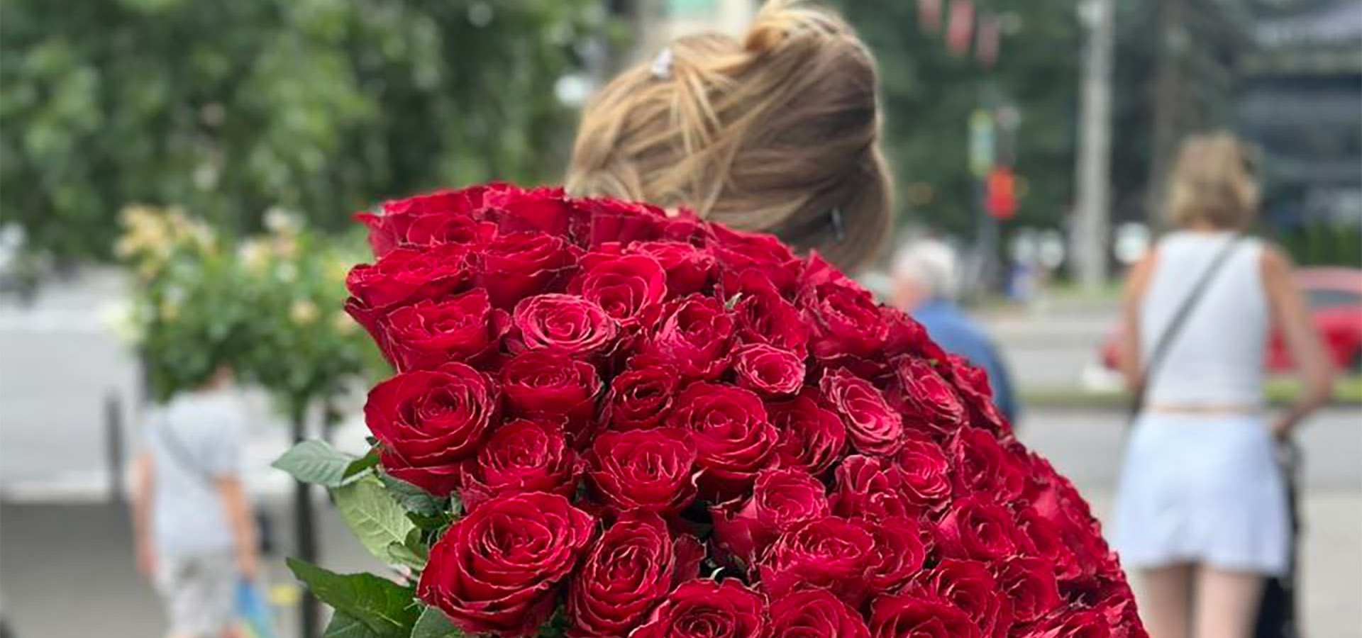 дівчина з великим букетом червоних троянд